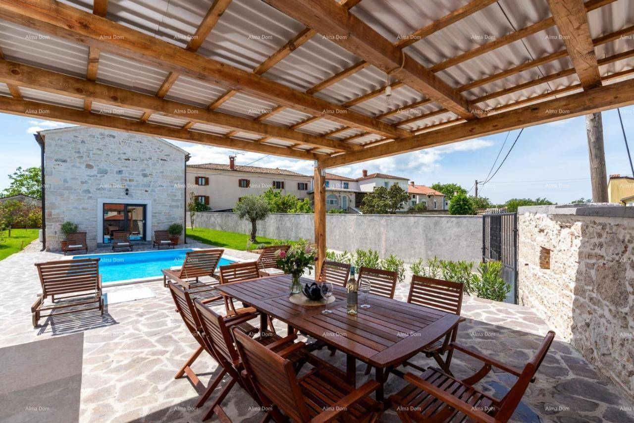 Geräumige überdachte Terrasse mit Holztisch und Stühlen, angrenzend an den Poolbereich und umgeben von Natur.