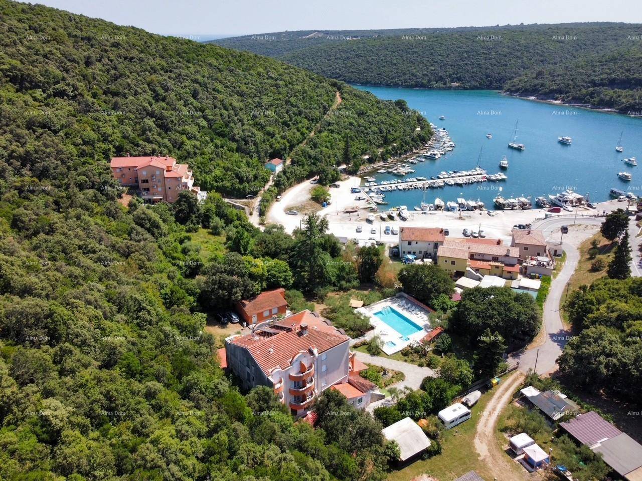 Luftaufnahme des Anwesens mit Pool, umgeben von üppiger Vegetation und Blick auf die Bucht mit Yachthafen.