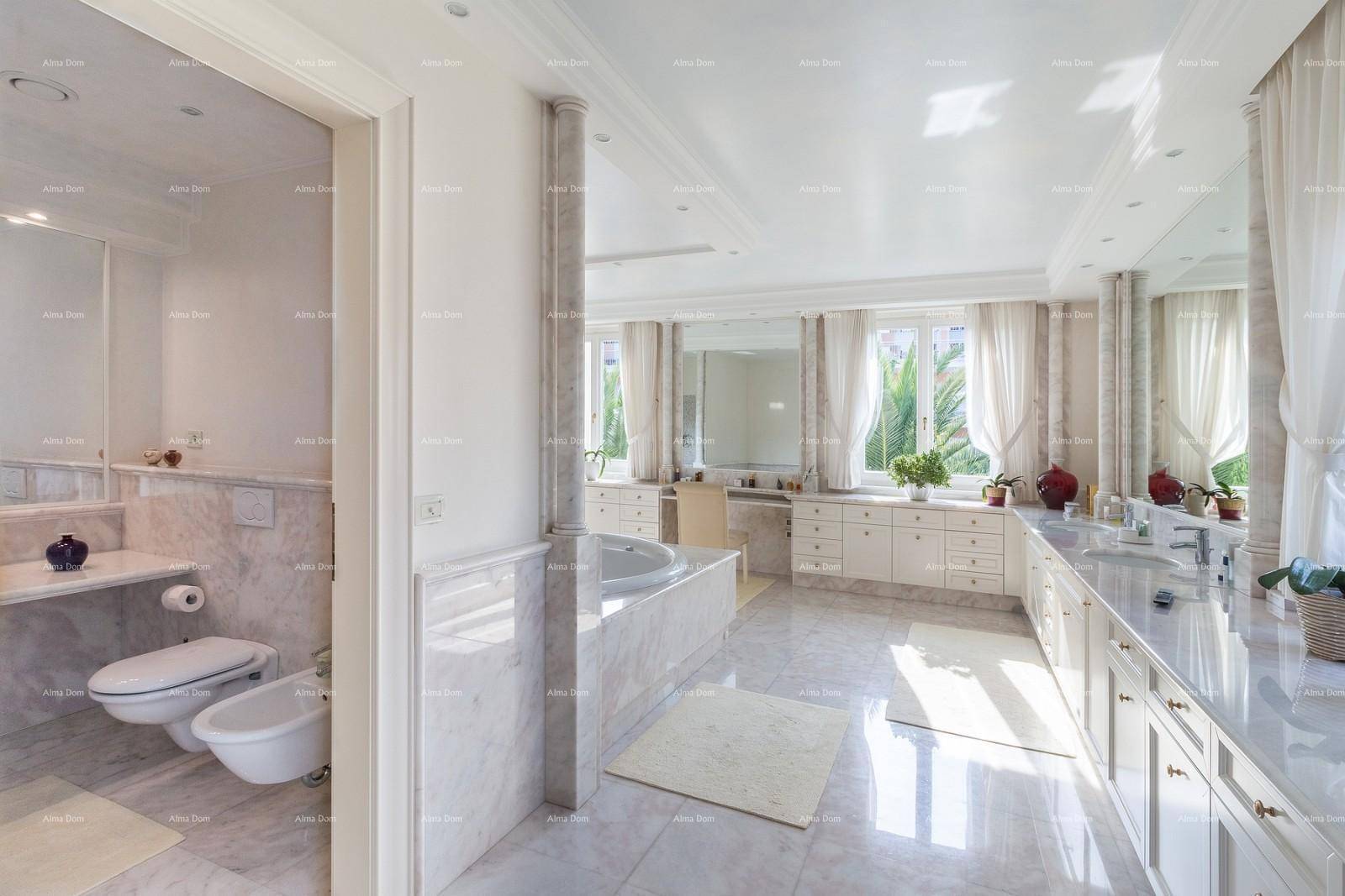 Luxuriöses Badezimmer mit Marmorfliesen, großer Badewanne, Doppelwaschbecken und Fenster.