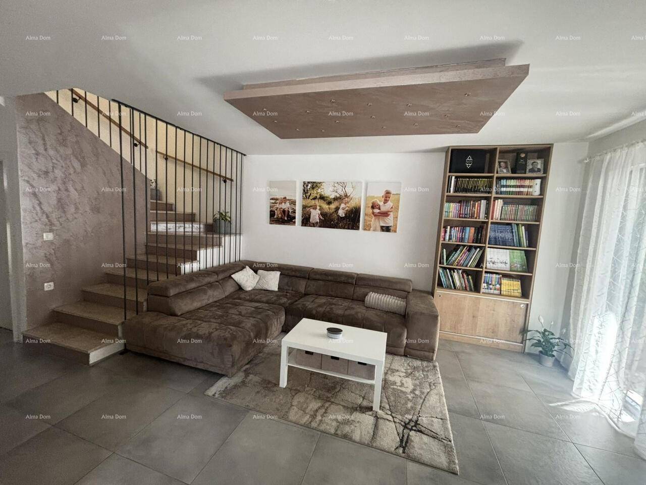 Geräumiges Wohnzimmer mit beigem Ecksofa, Bücherregal und moderner Deckenbeleuchtung.