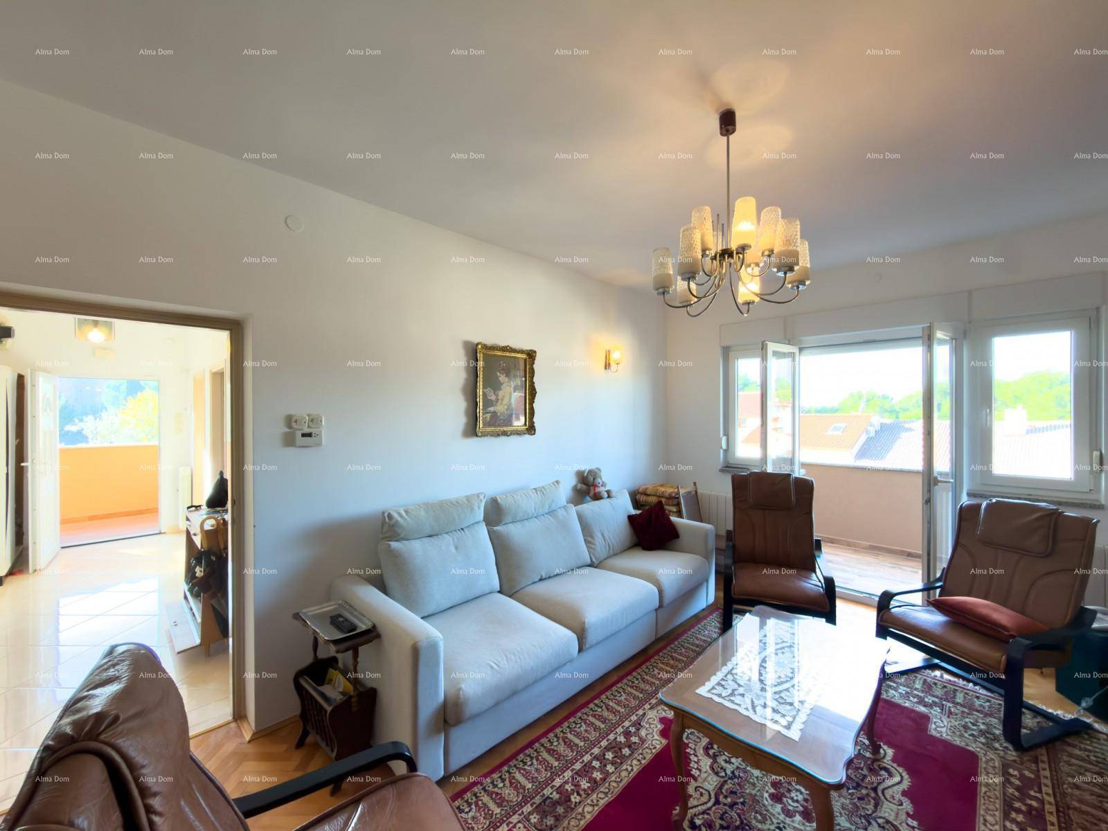Helles Wohnzimmer mit beigem Sofa, Teppich und Zugang zu einem Balkon mit Aussicht.