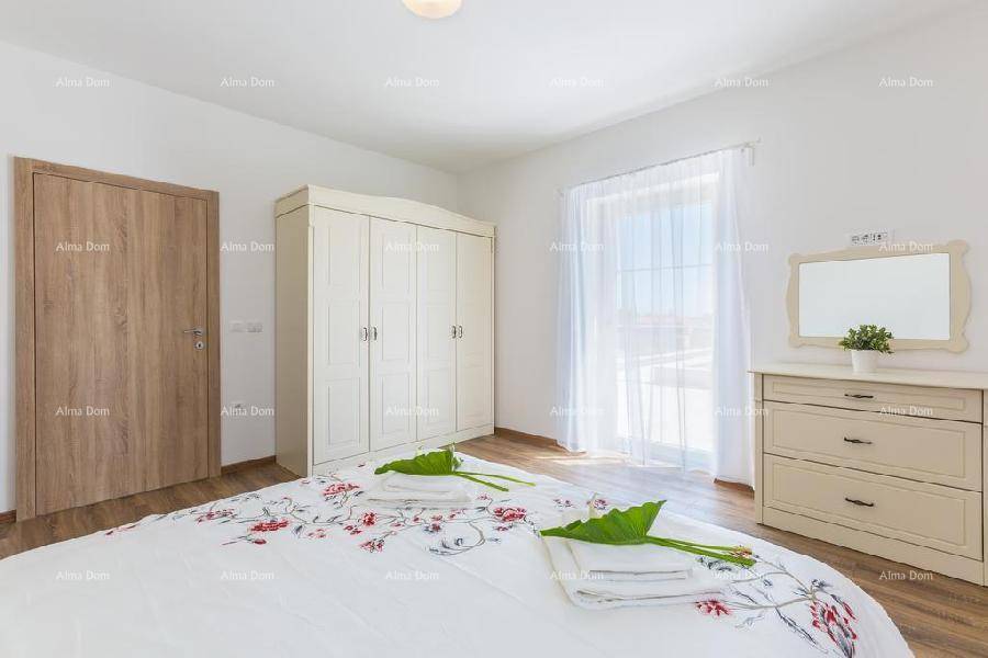Schlafzimmer mit weißem Kleiderschrank, Kommode und Zugang zum Balkon durch eine Fenstertür.