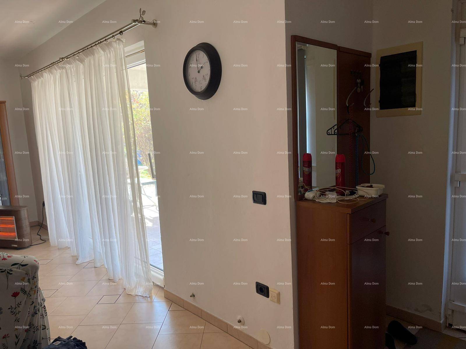 Heller Eingangsbereich mit Garderobe, großem Fenster und Vorhängen.