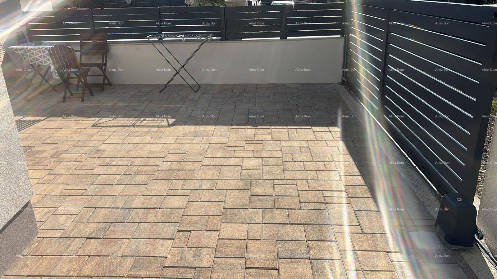 Gepflasterte Terrasse mit Sitzgelegenheiten und einem modernen Sichtschutzzaun, ideal für Entspannung im Freien.