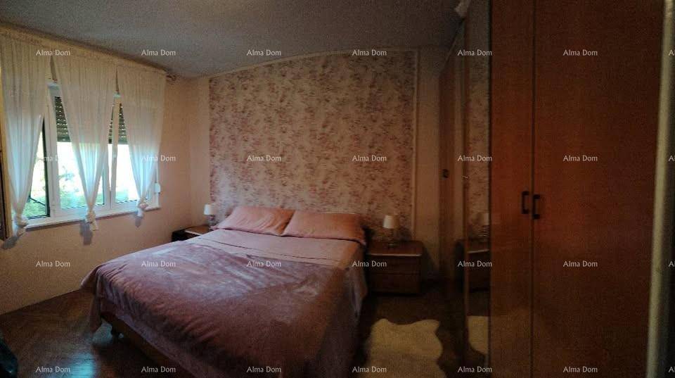 Schlafzimmer mit Doppelbett, gemusterter Tapete und einem großen Holzschrank, bietet eine warme Atmosphäre.
