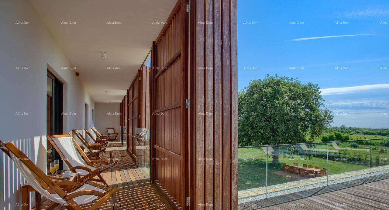Langer Balkon mit Holzdeck, Liegestühlen und Glasgeländer, bietet weite Aussicht ins Grüne.