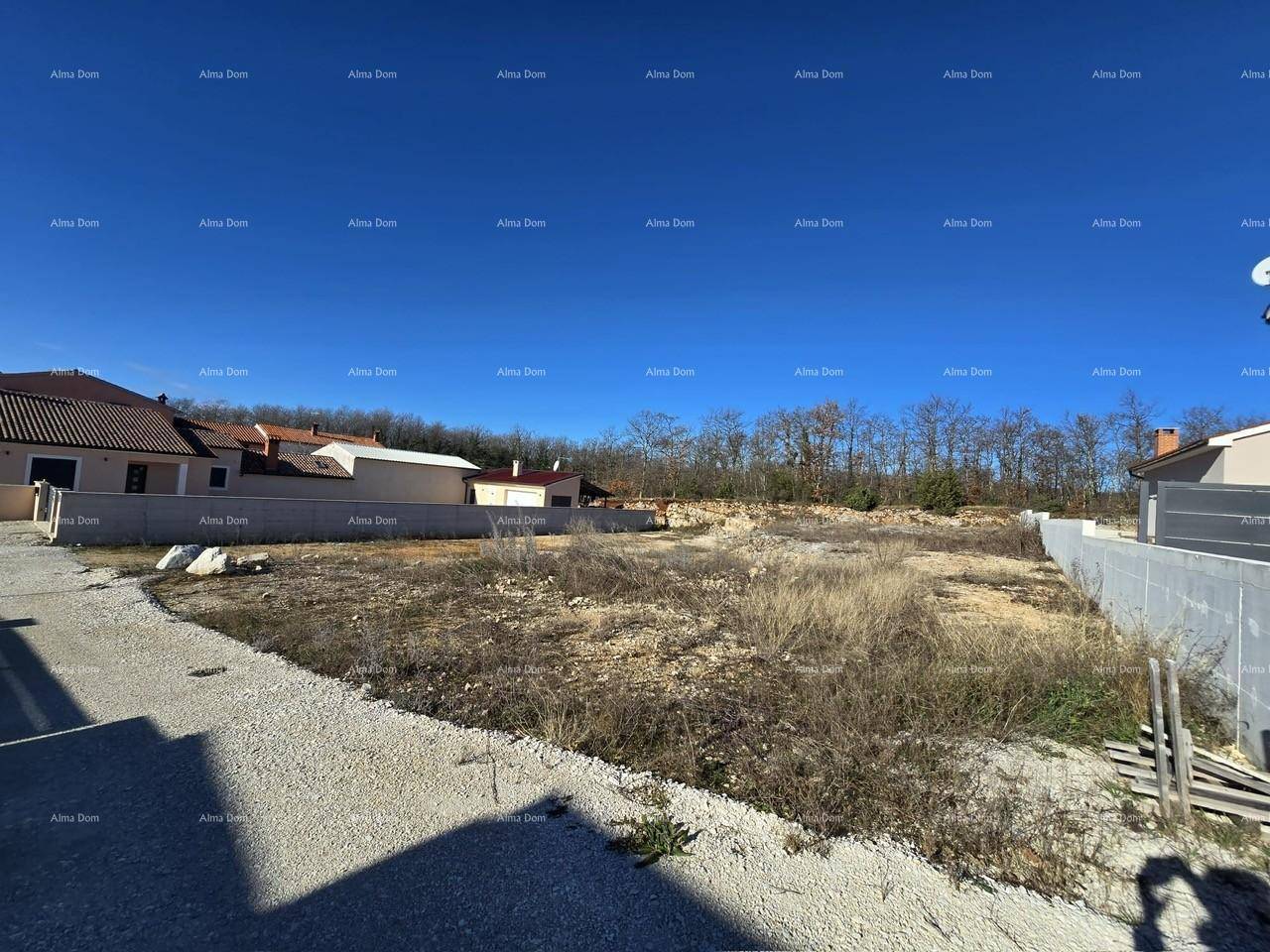 Panoramablick auf ein unbebautes Grundstück mit Schotterweg und umliegender Natur.