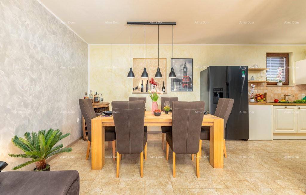 Geräumiger Essbereich mit Holztisch, bequemen Stühlen und Blick auf die offene Küche im Hintergrund.
