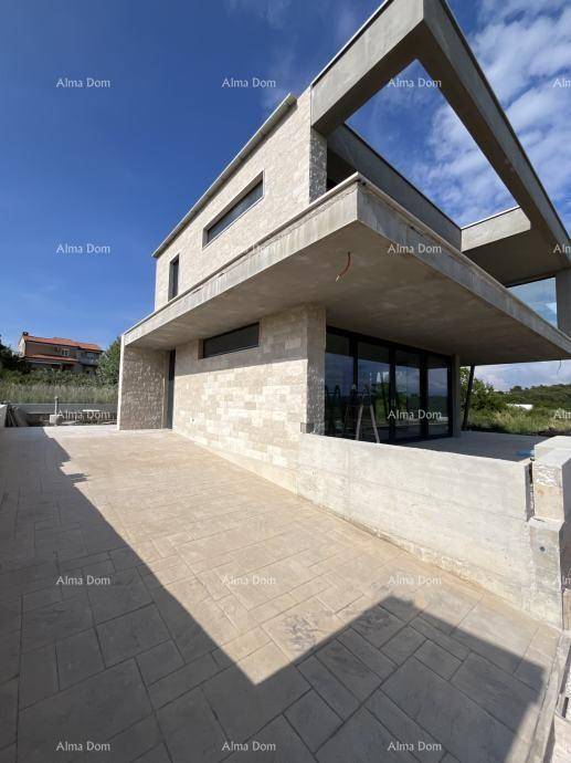 Moderne Architektur eines Neubaus mit heller Steinfassade und gepflasterter Zufahrt.