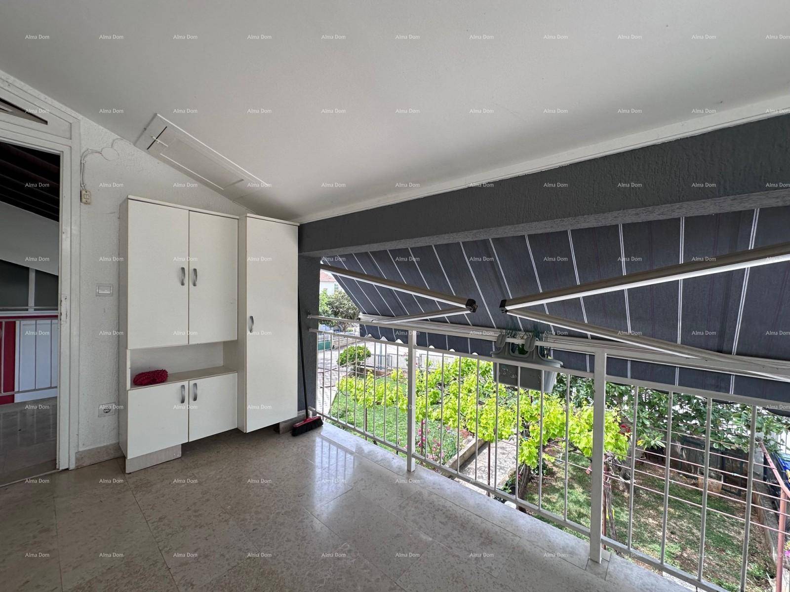 Geräumiger Balkon mit praktischen weißen Schränken, Markise und Blick auf den Garten.