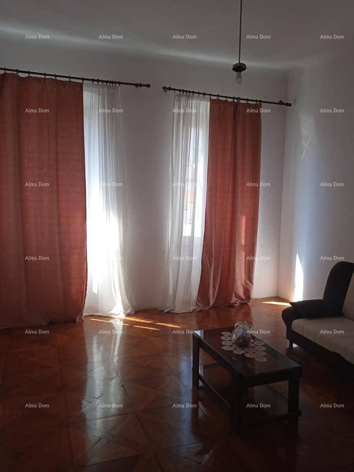 Helles Wohnzimmer mit Fischgrätparkettboden und zwei Fenstern, die viel natürliches Licht hereinlassen.