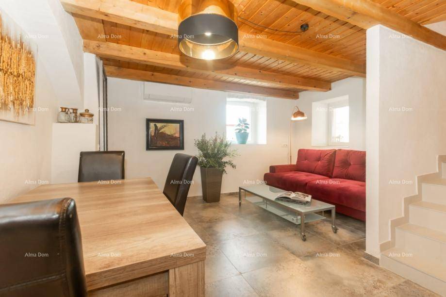 Wohn-Essbereich mit Holzbalkendecke, rotem Sofa und Esstisch, ausgestattet mit Klimaanlage.