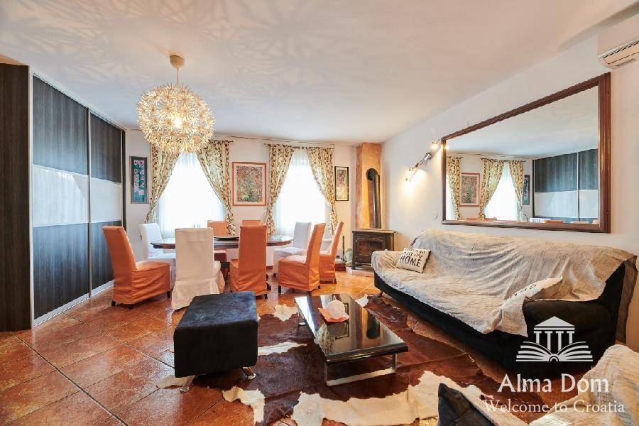 Wohn- und Essbereich mit großem Spiegel, Esstisch und gemütlichem Sofa auf Fliesenboden.