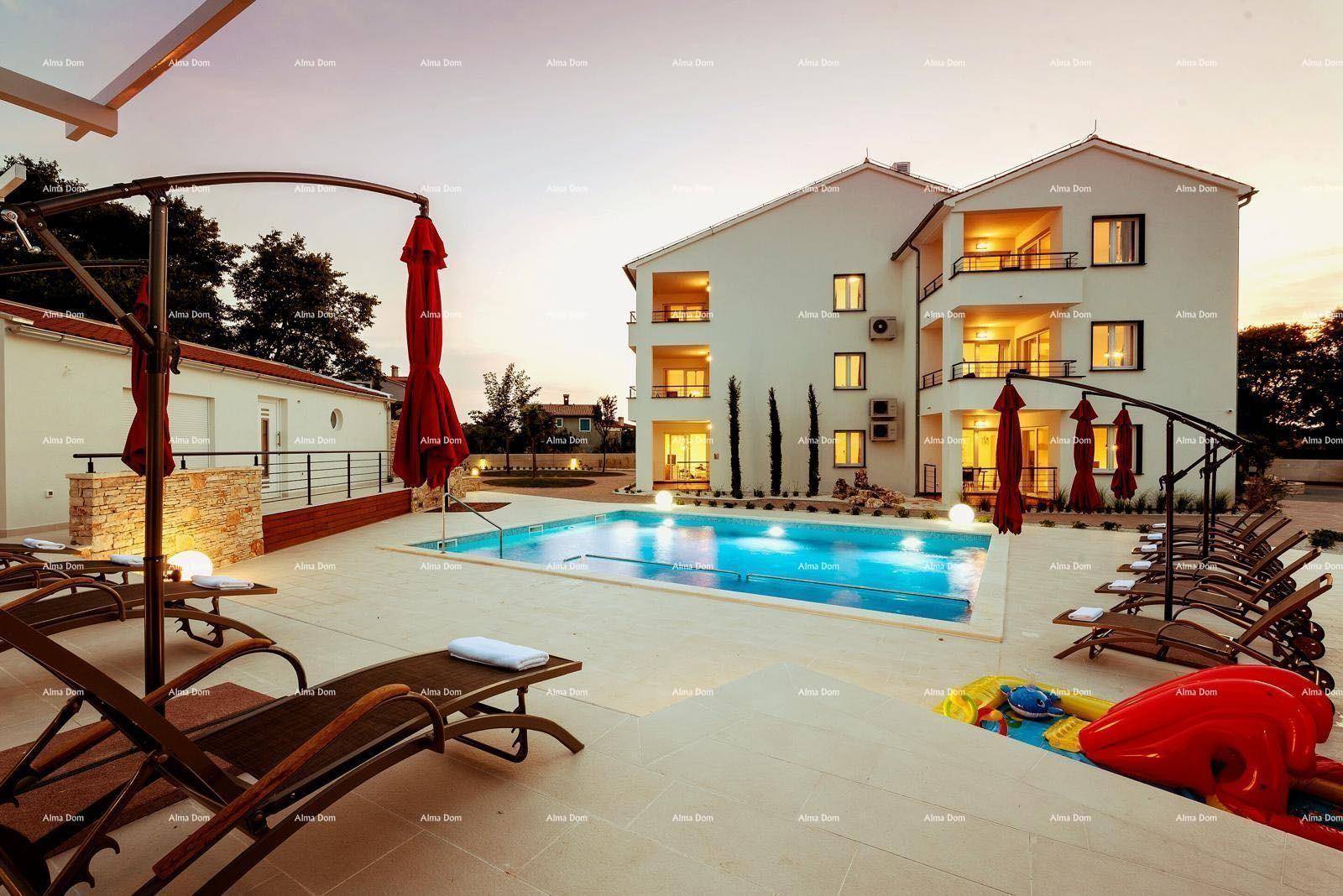 Abendliche Ansicht des Pools mit Liegestühlen und beleuchtetem Gebäude bei Sonnenuntergang.