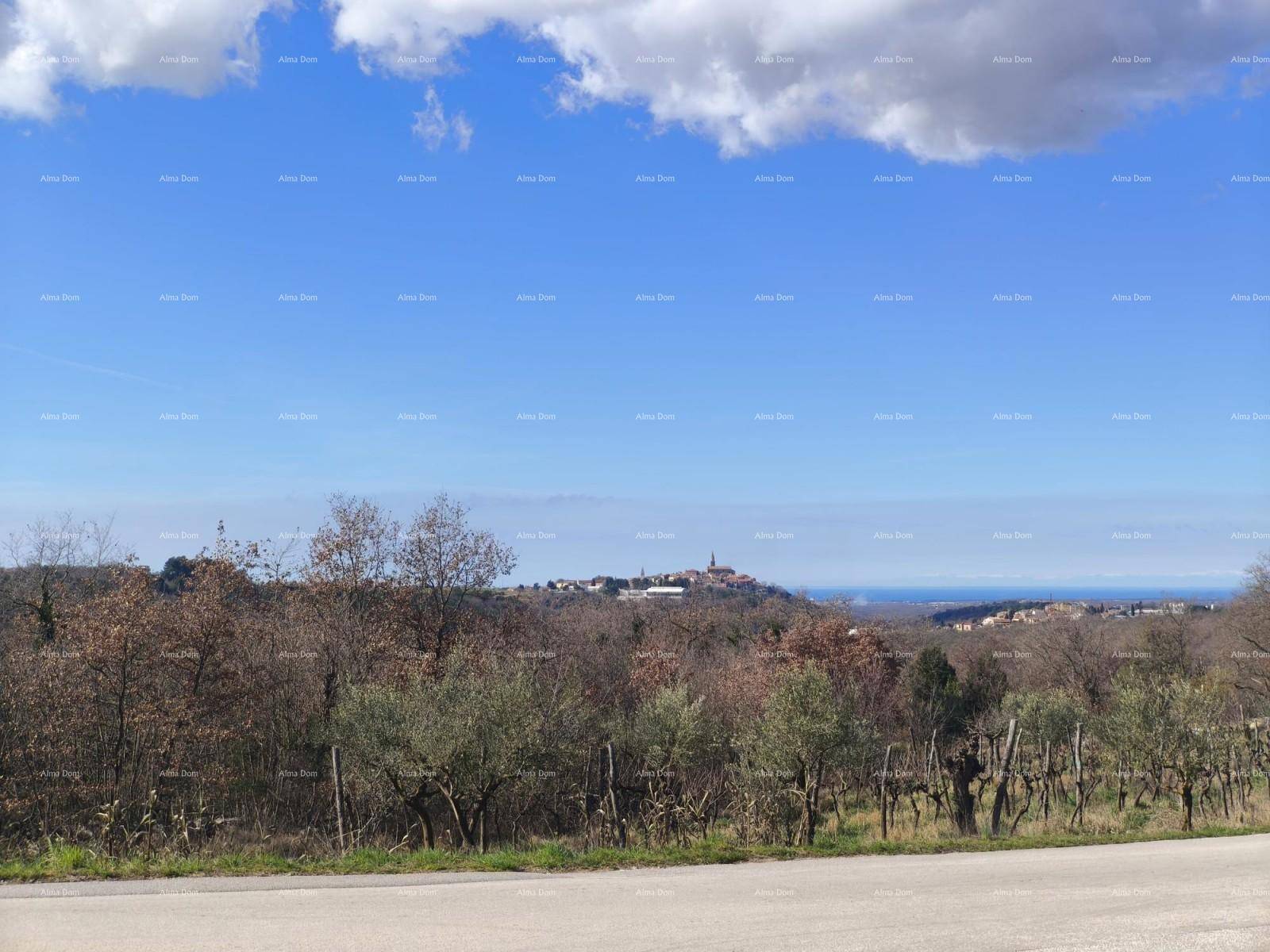 Panoramablick über eine ländliche Landschaft mit einem Dorf auf einem Hügel und dem Meer in der Ferne.
