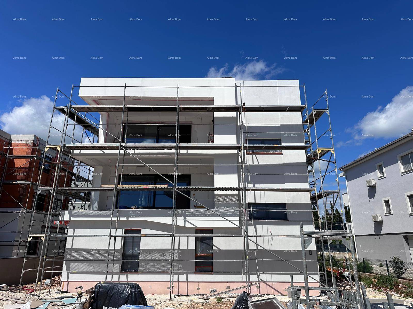 Fassade eines im Bau befindlichen Gebäudes mit Gerüst und sichtbarer Isolierung.