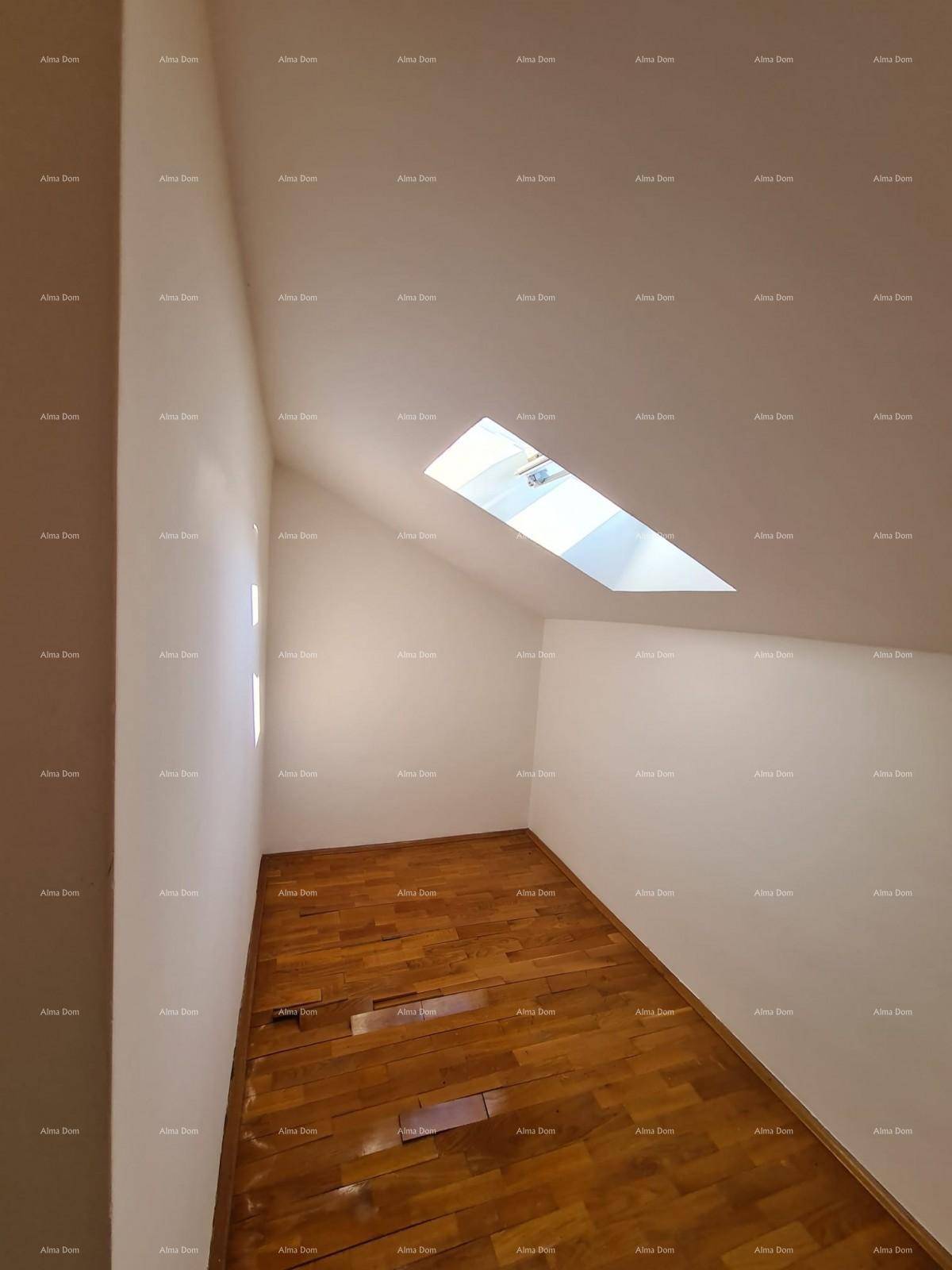 Geräumiges Dachzimmer mit Holzparkettboden, weißen Wänden und einem schrägen Dachfenster.