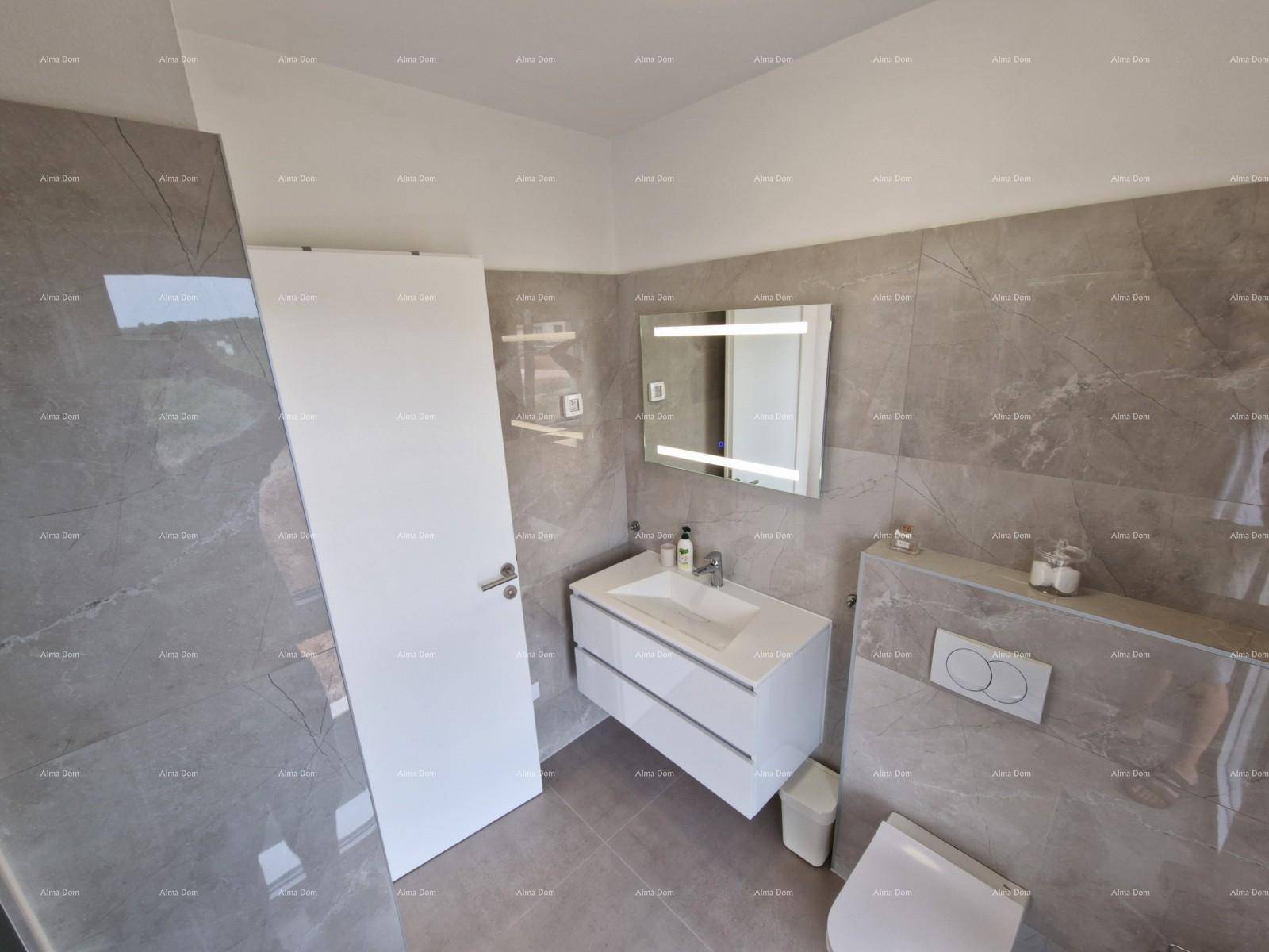 Elegantes Badezimmer mit grauen Großformatfliesen, schwebendem Waschtisch und beleuchtetem Spiegel.