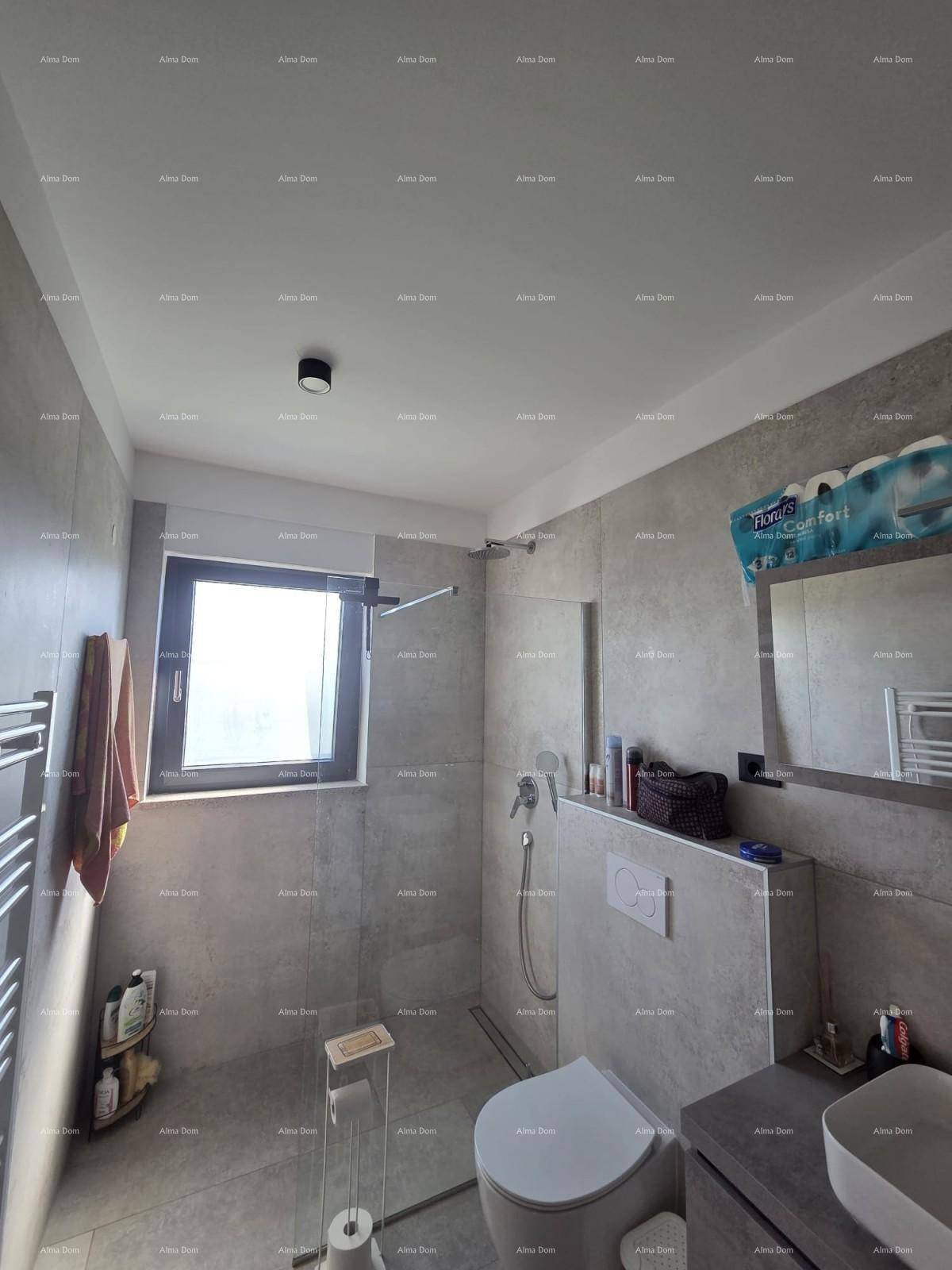 Modernes Badezimmer mit grauen Fliesen, bodengleicher Dusche und Fenster für Tageslicht.