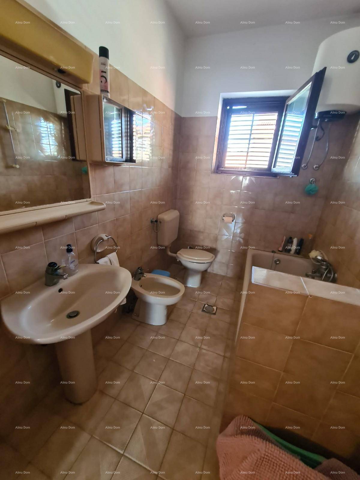 Badezimmer mit beigen Fliesen, Waschbecken, Toilette und Bidet, bietet grundlegende Ausstattung.