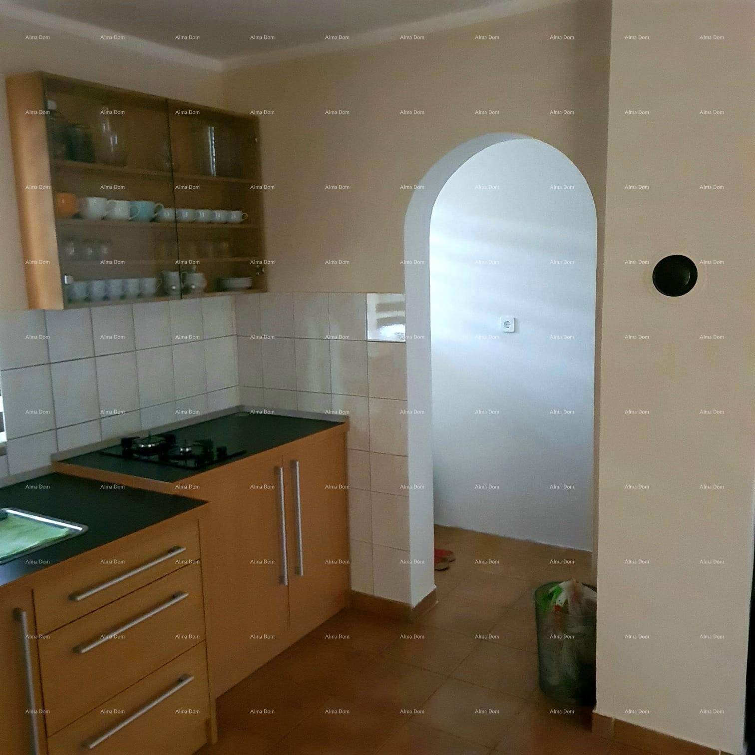 Küche mit Holzschränken und Fliesenboden, verbunden durch einen Rundbogen mit einem weiteren Raum.