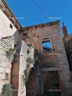 Außenansicht des historischen Steinhauses mit charakteristischen Steinmauern und leeren Fensteröffnungen unter blauem Himmel.