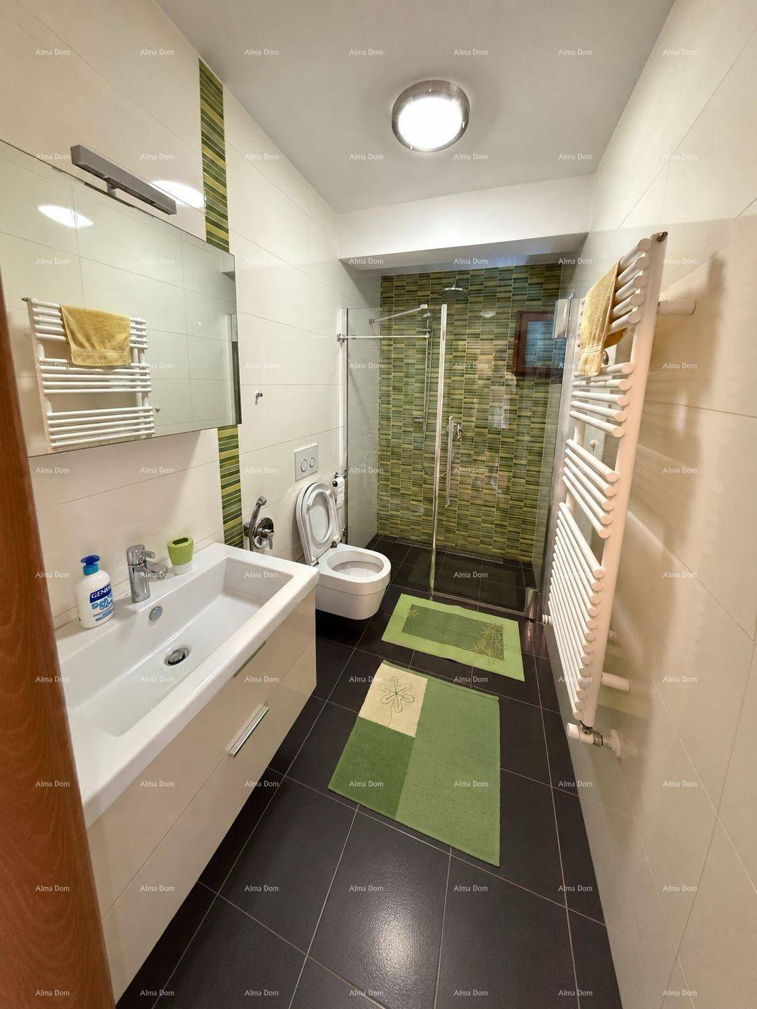 Helles Badezimmer mit Dusche, WC, Waschtisch und grünen Akzentfliesen.