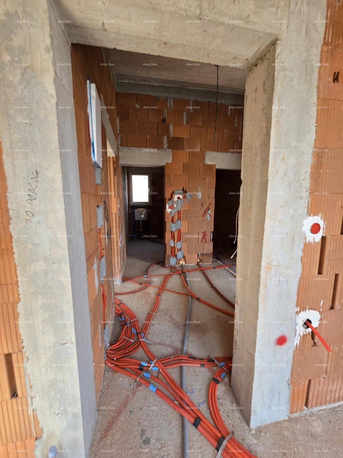 Flur im Rohbau mit sichtbaren Ziegelwänden und verlegten Elektroinstallationen.