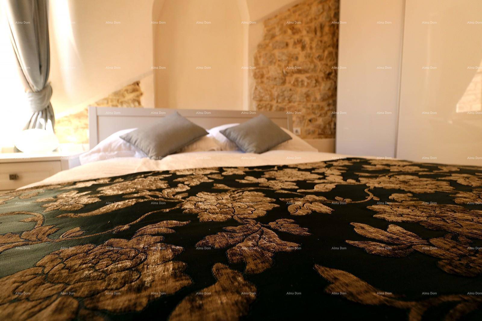 Gemütliches Schlafzimmer mit Doppelbett, floraler Bettdecke und freigelegter Steinwand.