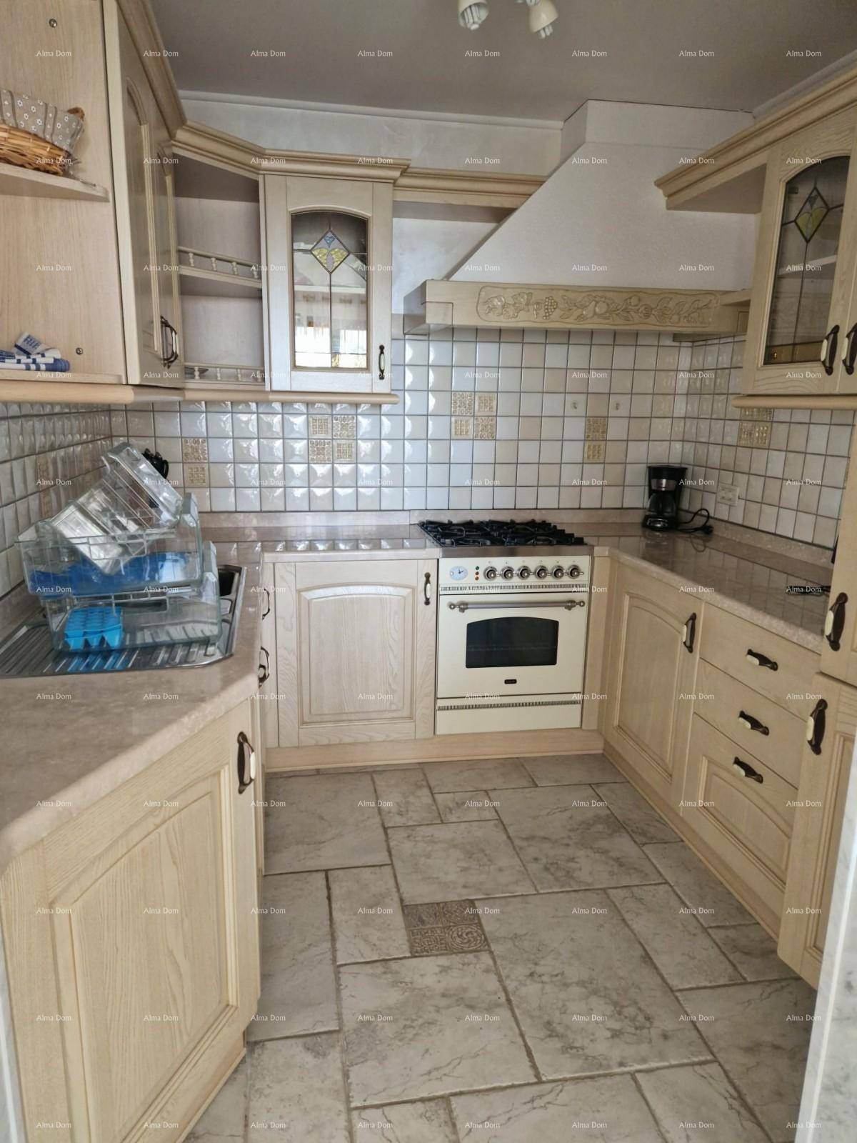 Helle Küche mit beigen Holzschränken, Gasherd und Fliesenboden.