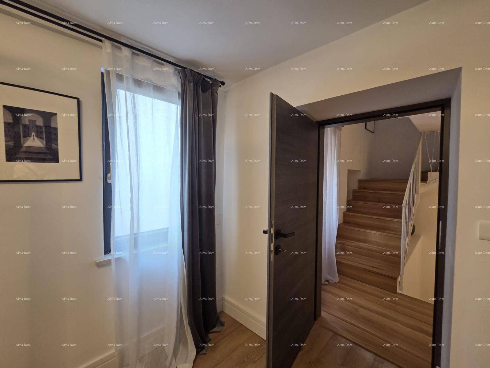 Heller Flur mit Fenster, Vorhängen und einer offenen Tür, die zu einer Holztreppe führt.