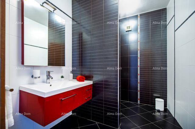 Modernes Badezimmer mit rotem Waschtischunterschrank, Spiegel und dunklen Fliesen.