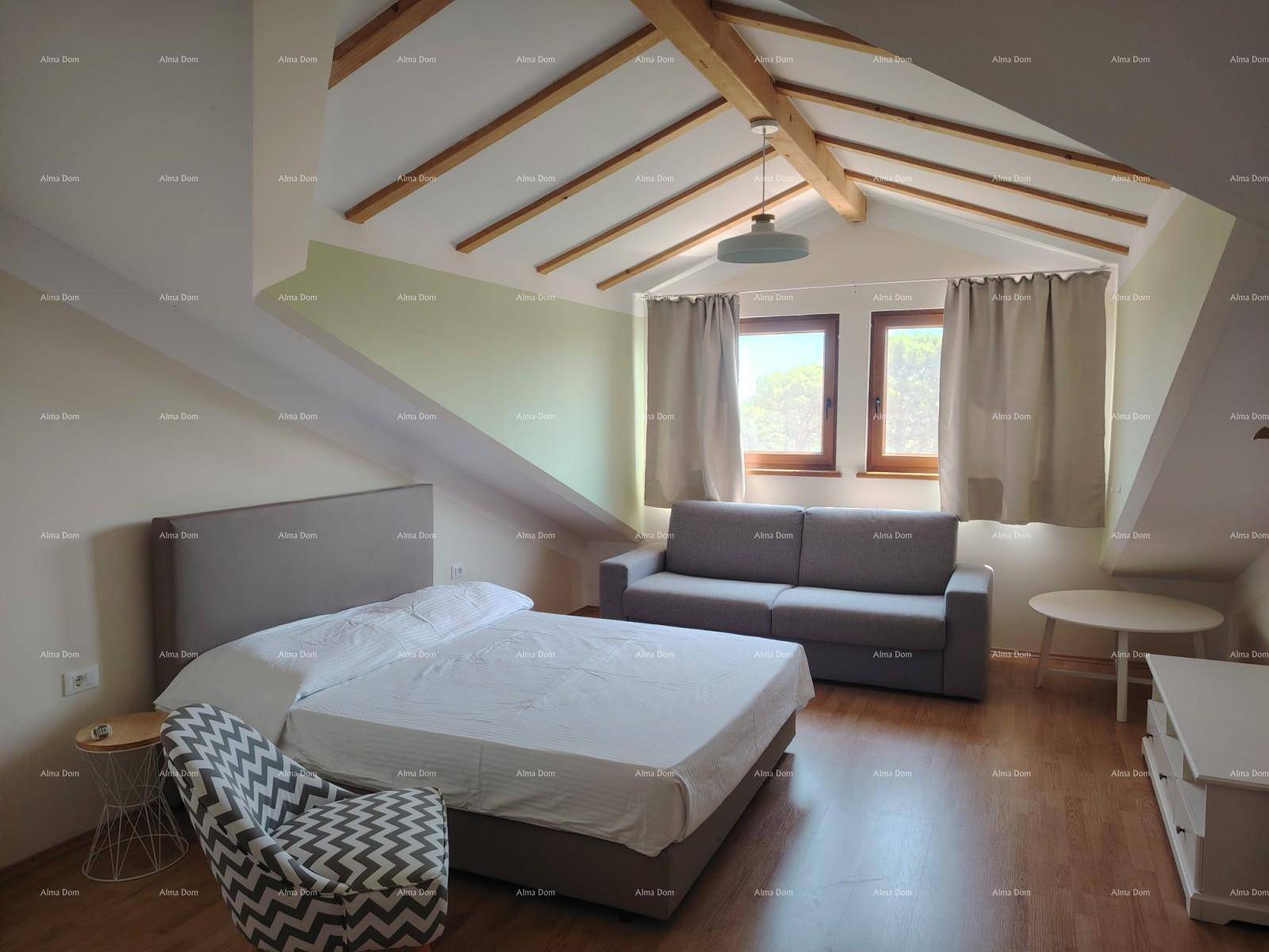 Gemütliches Dachgeschoss-Schlafzimmer mit sichtbaren Holzbalken, Doppelbett und bequemer Couch.