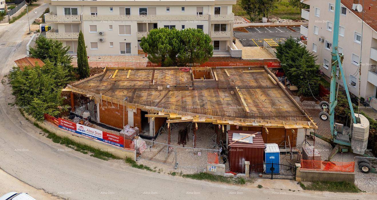 Übersicht der Baustelle eines neuen Gebäudes mit sichtbaren Bauarbeiten und angrenzenden Wohnhäusern.