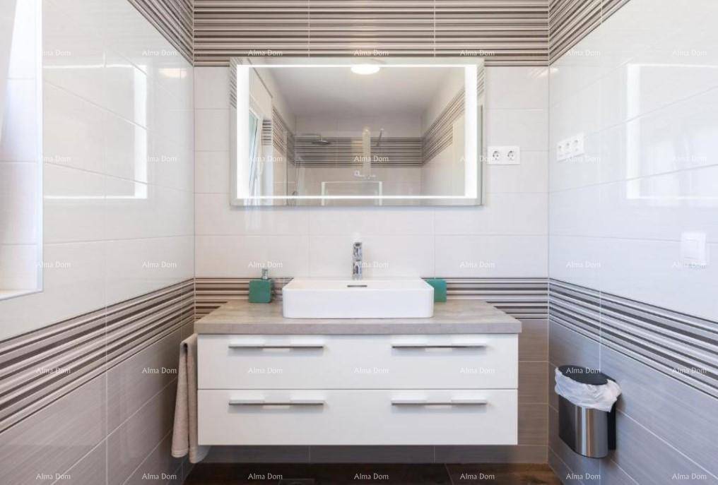 Modernes Badezimmer mit weißem Waschtisch, Aufsatzwaschbecken und beleuchtetem Spiegel.