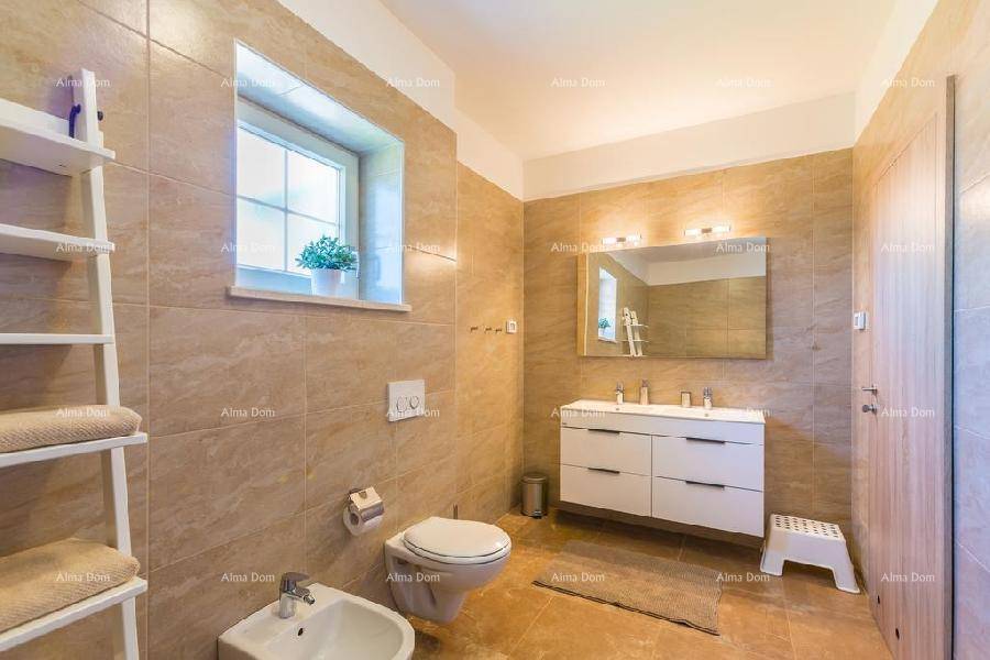 Modernes Badezimmer mit beigefarbenen Fliesen, WC, Bidet und einem Fenster für natürliche Belüftung.