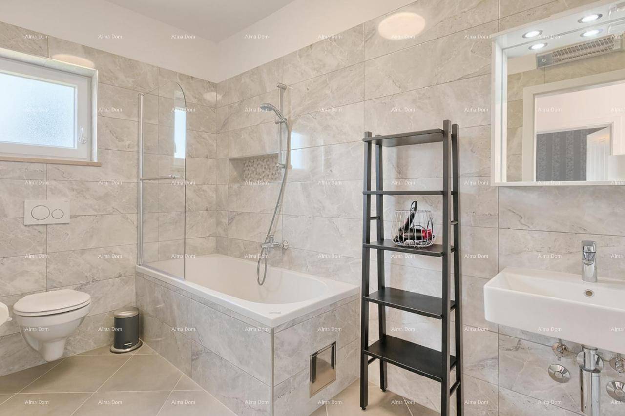 Modernes Badezimmer mit Badewanne, Duschfunktion, WC und eleganten grauen Fliesen.