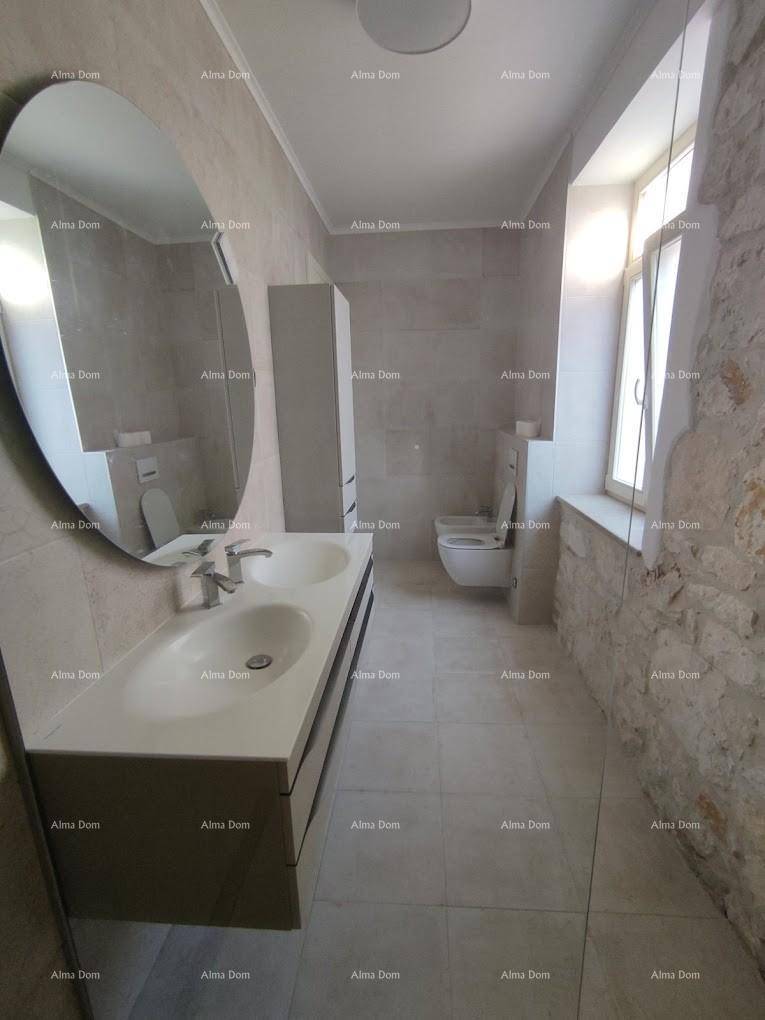 Modernes Badezimmer mit Doppelwaschbecken, wandhängendem WC, Steinwand und Fenster.