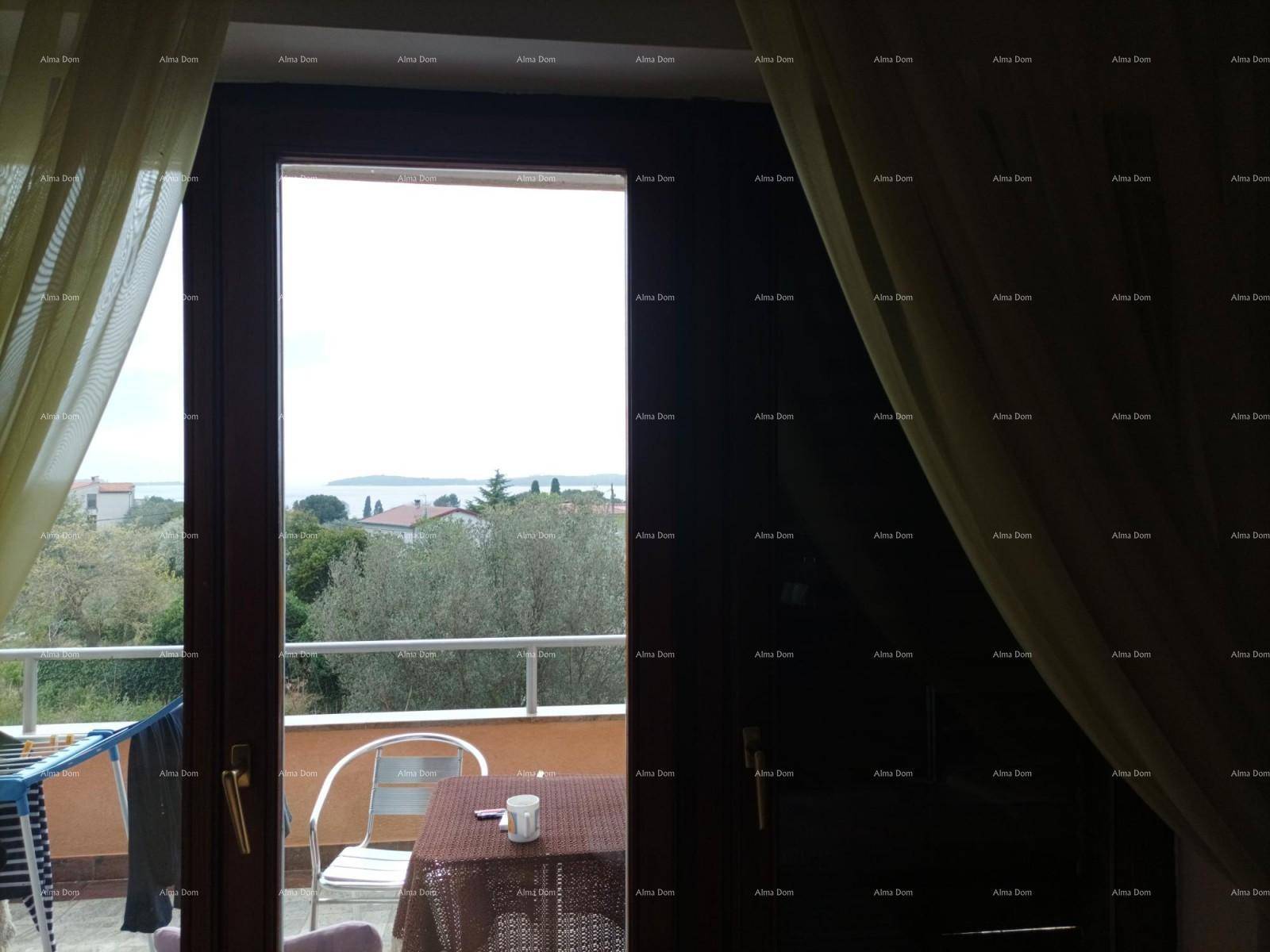 Blick aus einem Zimmer durch eine Glastür auf einen Balkon mit Tisch und Meerblick.