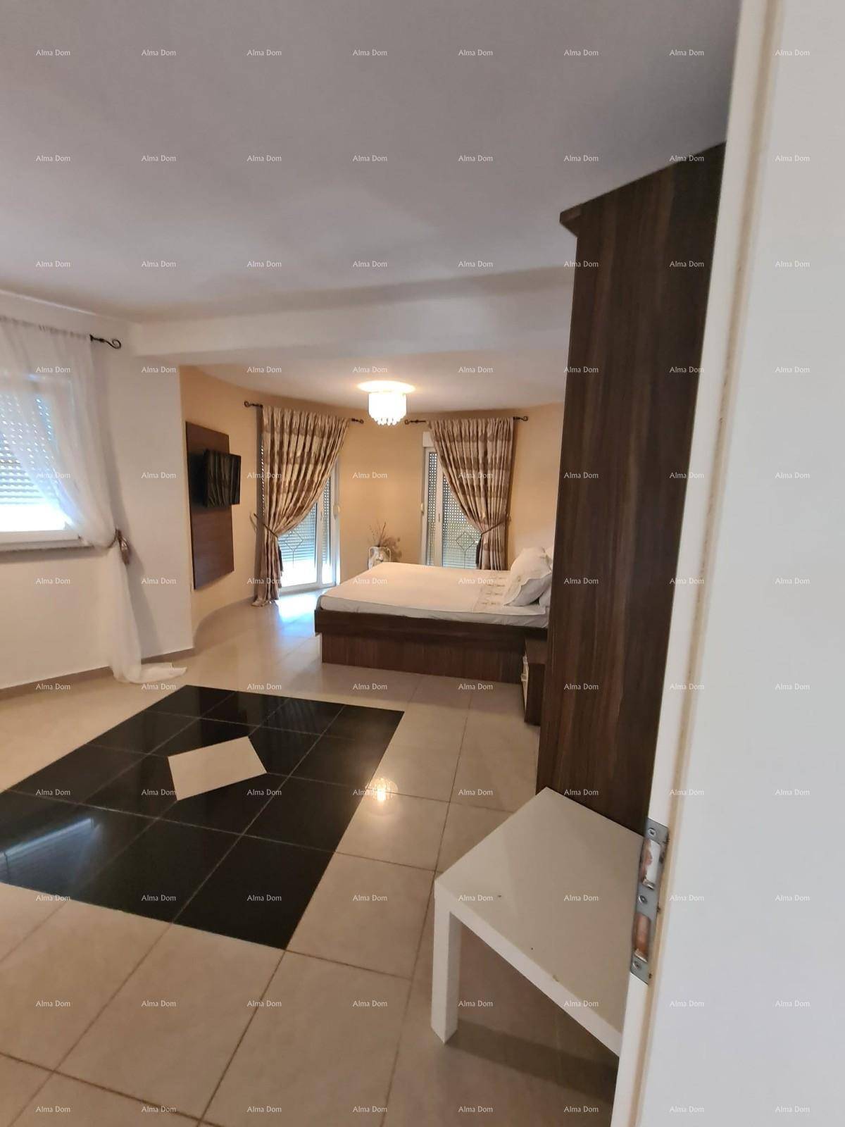 Geräumiges Schlafzimmer mit Fliesenboden, dunklem Kleiderschrank und Zugang zum Balkon.