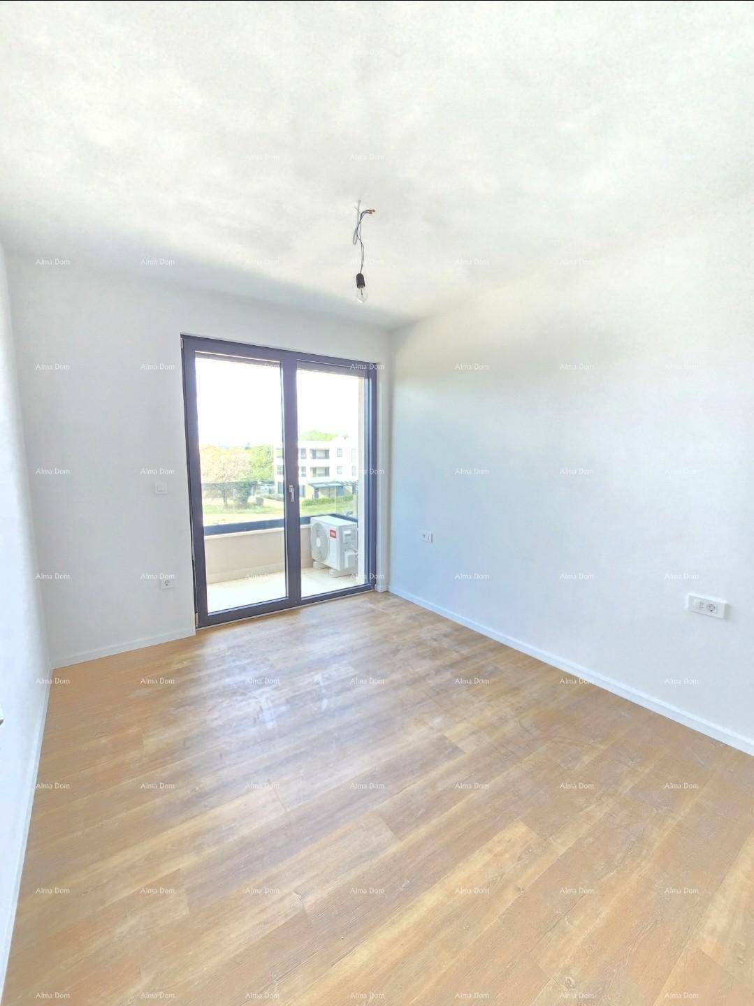 Helles, unmöbliertes Zimmer mit Holzboden und Zugang zu einem Balkon mit Klimaanlage.
