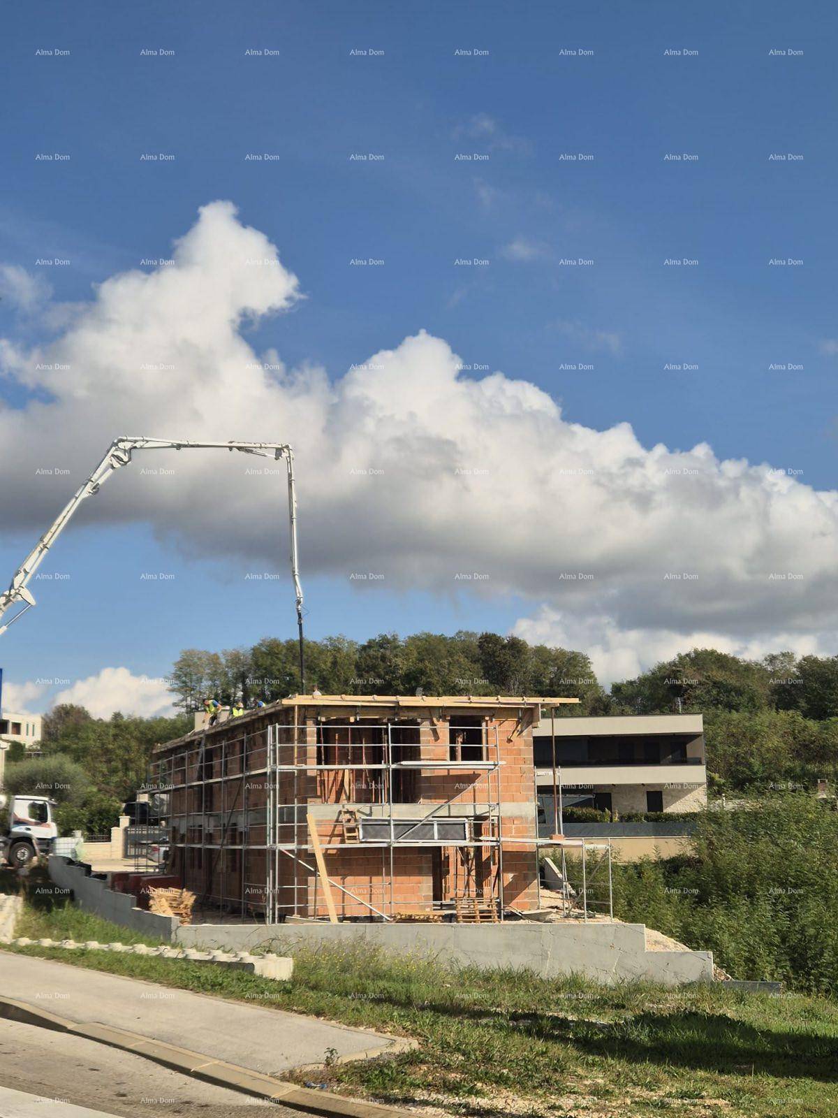 Baustelle eines neuen Wohngebäudes mit Gerüst und Betonpumpe unter blauem Himmel.