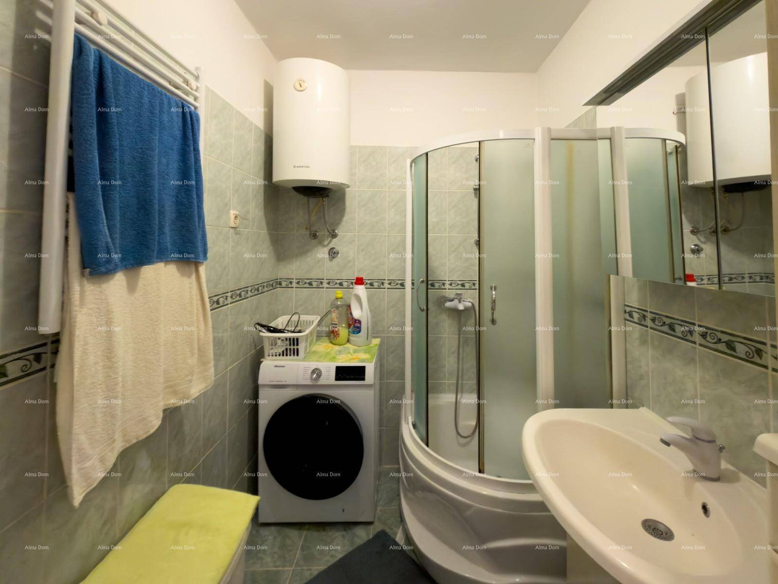 Badezimmer mit Duschkabine, Waschmaschine, Waschbecken und Fliesen an Wänden und Boden.