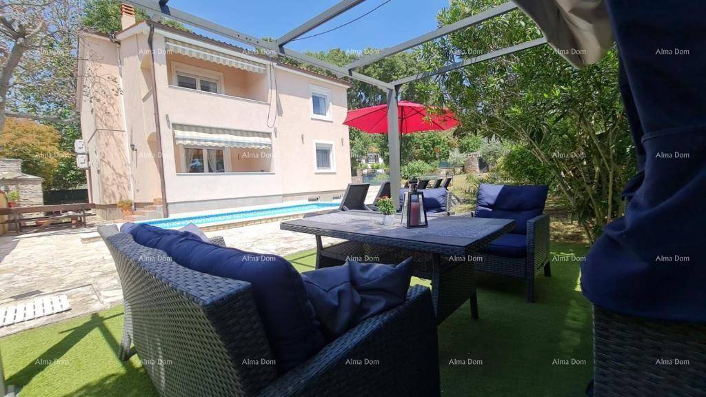 Gemütlicher Außenbereich unter einer Pergola mit bequemen Loungemöbeln und Blick auf den Pool.