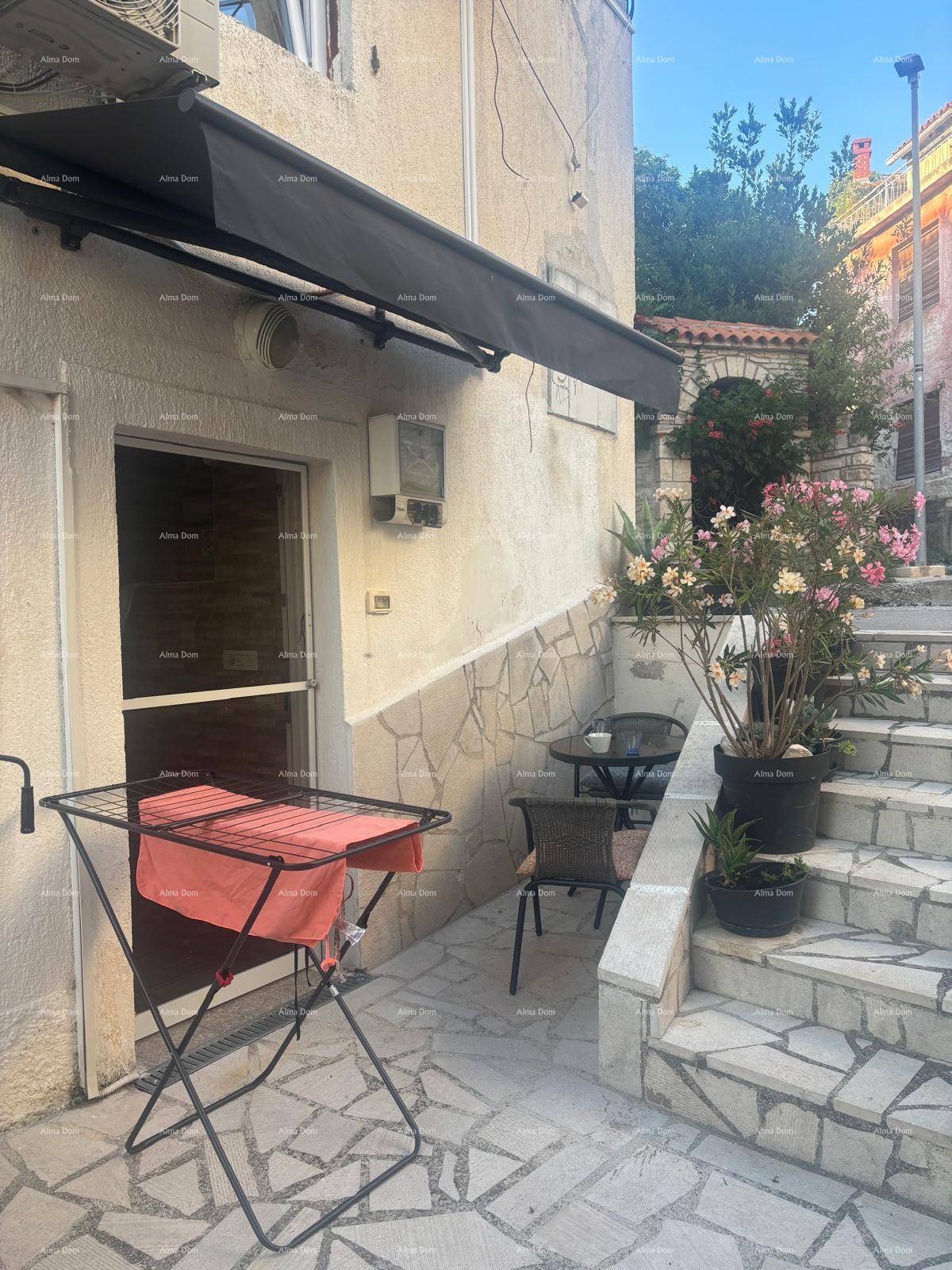 Gemütliche Terrasse mit Steinfliesen, Markise und Außentreppe in mediterraner Umgebung.