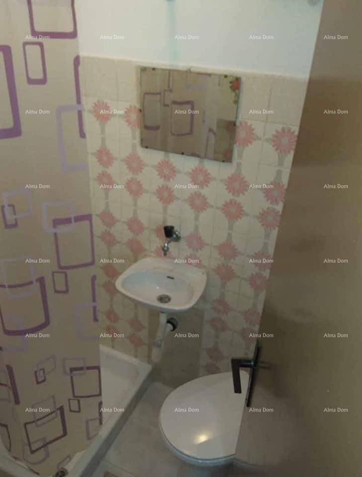 Kleines Badezimmer mit rosa gemusterten Fliesen, Waschbecken und Toilette.