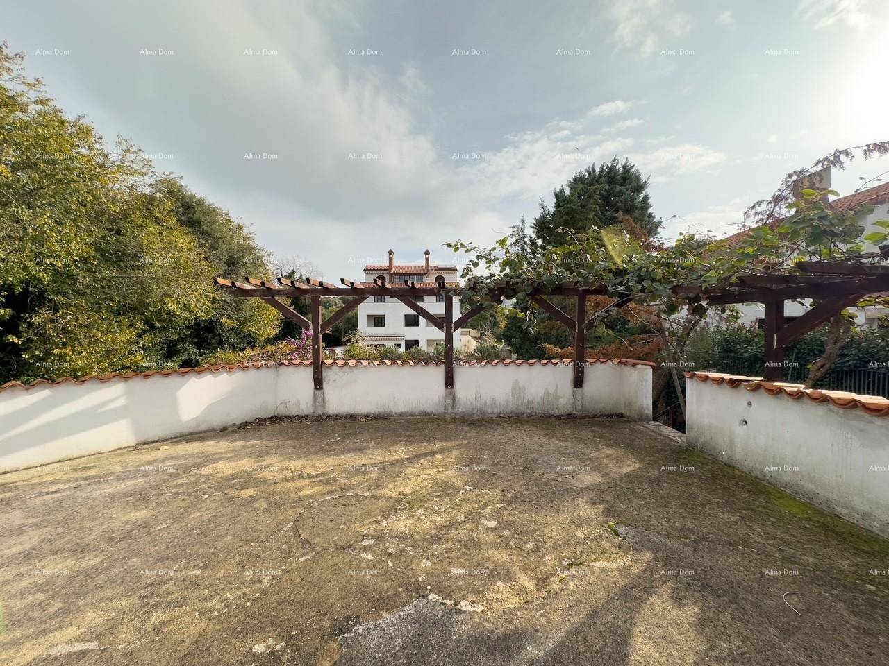 Blick über den Gartenbereich mit Pergola auf das Hauptgebäude im Hintergrund, umgeben von viel Grün.