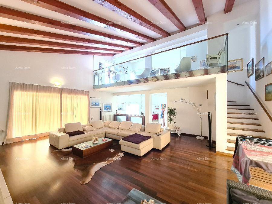 Geräumiges Wohnzimmer mit hohen Decken, Holzbalken und einer offenen Galerie mit Glasgeländer.