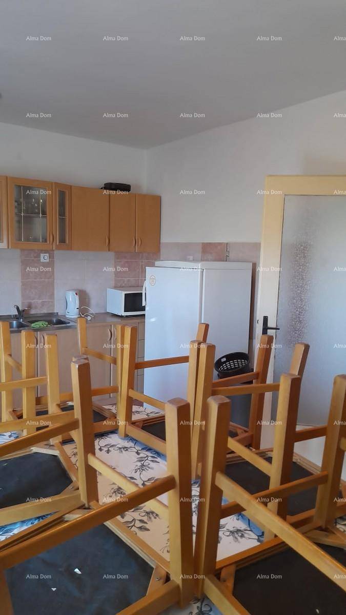 Küche mit hellen Holzschränken, Kühlschrank und einem Esstisch, der aufgeräumt wird.
