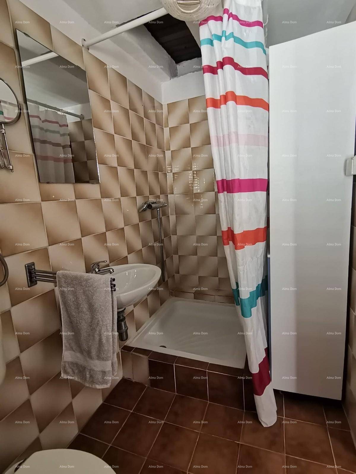Badezimmer mit Duschbereich, Waschbecken und Spiegel, gefliest in Brauntönen.
